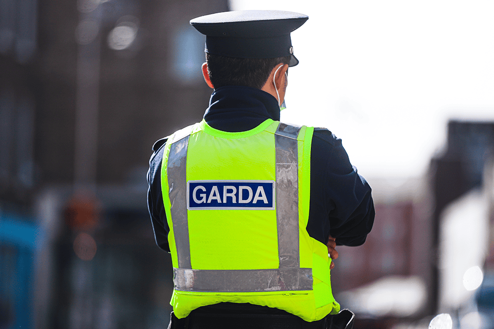 Garda officer in high visibility vest patrolling on city street, crime prevention, community safety.